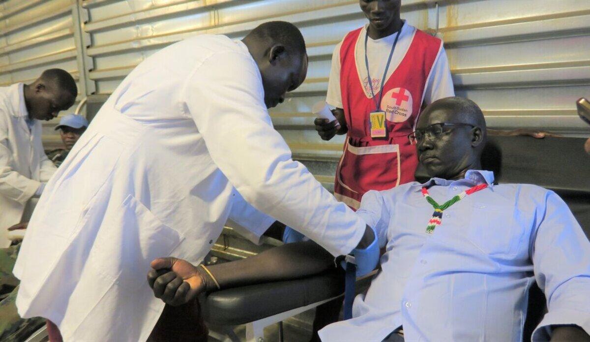 A health worker attending to a seated person
