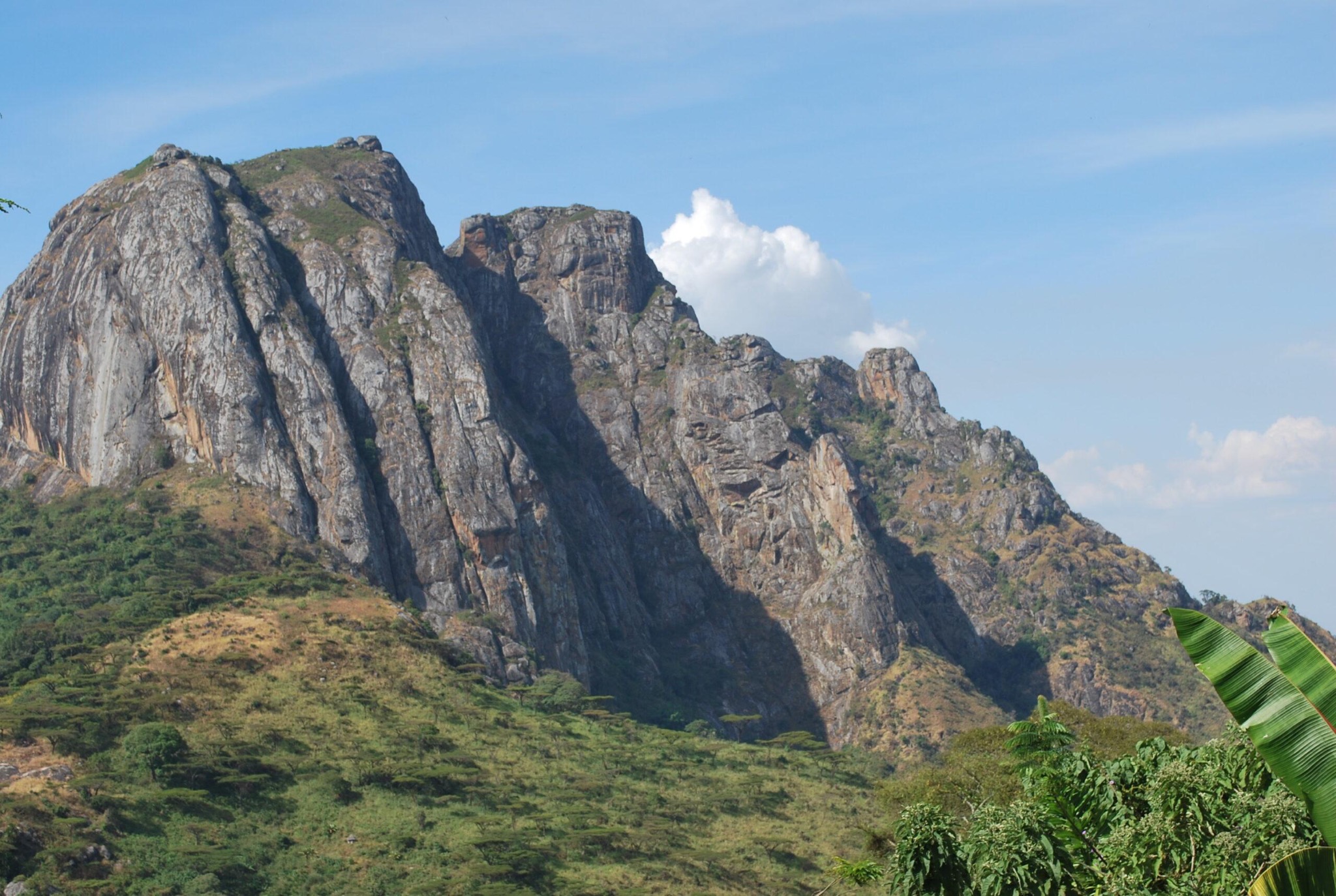 A steep rocky mountain above a green valley
